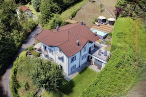 A two-story house with a red roof, a swimming pool, and a well-maintained lawn. - villa Casasco - MyHomeinComo (Casasco d'Intelvi)