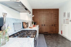 Eine moderne Küche mit Gaskochfeld, Holzschränken und einer Marmor-Spritzschutzwand.