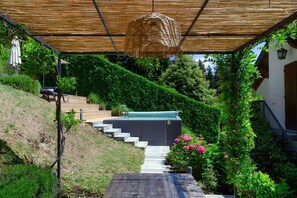 Un espacio al aire libre cubierto con una escalera que lleva a una piscina, rodeado de vegetación exuberante y una pérgola.