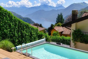Una piscina con vistas a montañas y un lago, rodeada de vegetación y edificios.