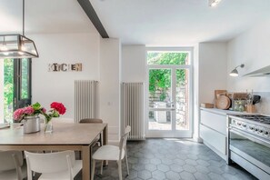 A modern kitchen with a dining area, a large window, and a view of greenery. - villa Casasco - MyHomeinComo (Casasco d'Intelvi)