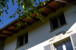 A building with a wooden roof, multiple windows, and a circular architectural detail on the facade. - villa Casasco - MyHomeinComo (Casasco d'Intelvi)