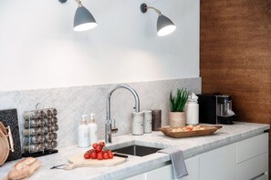 A modern kitchen with a marble countertop, a built-in sink, and overhead lighting. - villa Casasco - MyHomeinComo (Casasco d'Intelvi)