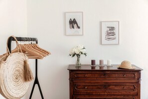 A room with a wooden dresser, a wall-mounted rack with bags, framed artwork, and a vase with flowers. - villa Casasco - MyHomeinComo (Casasco d'Intelvi)