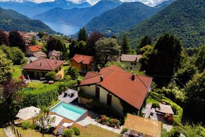 A residential area with houses, a swimming pool, and a view of mountains and a lake.