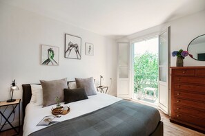 Un dormitorio con cama, mesitas de noche, cómoda y balcón con vistas.