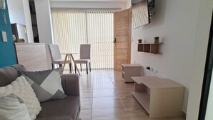 Una sala de estar moderna con un sofá, sillas, una mesa de centro y un televisor montado en la pared.