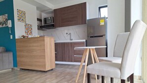 Una cocina moderna con microondas integrado, un refrigerador de acero inoxidable y un armario de madera.