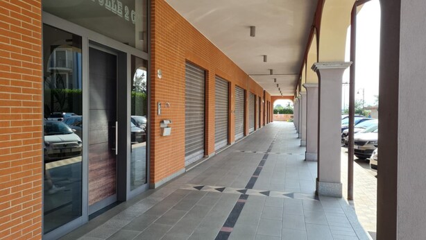 A covered corridor with a brick facade, large windows, and a tiled floor. - Turin Airport apartment G (Leinì)