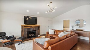 Una sala de estar moderna con chimenea, sofá de cuero y televisor de pantalla plana.