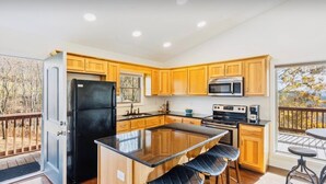 Una cocina moderna con armarios de madera, un refrigerador negro, un microondas y una estufa.