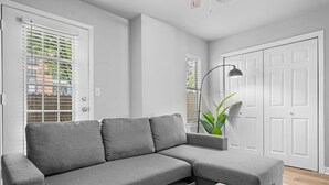 Een moderne woonkamer met een grijze hoekbank, een houten salontafel en een vloerlamp.