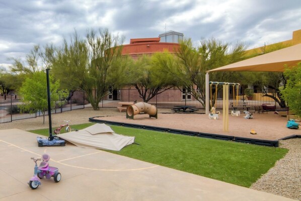 A playground with a slide, swings, and a sandbox.