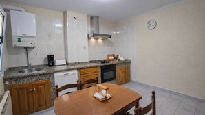 Een kleine keuken met een vaatwasser, fornuis en een klok aan de muur.