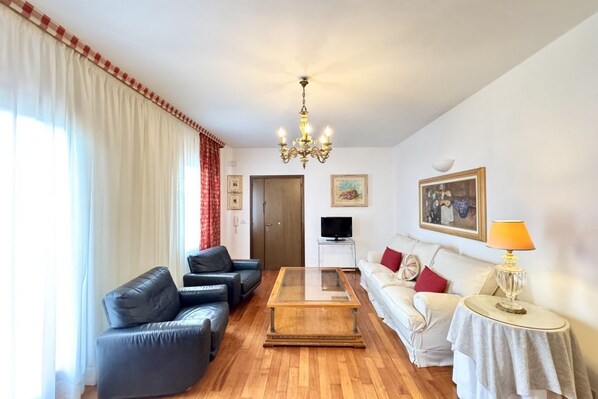 A living room with a wooden coffee table, two sofas, a TV, and a chandelier.