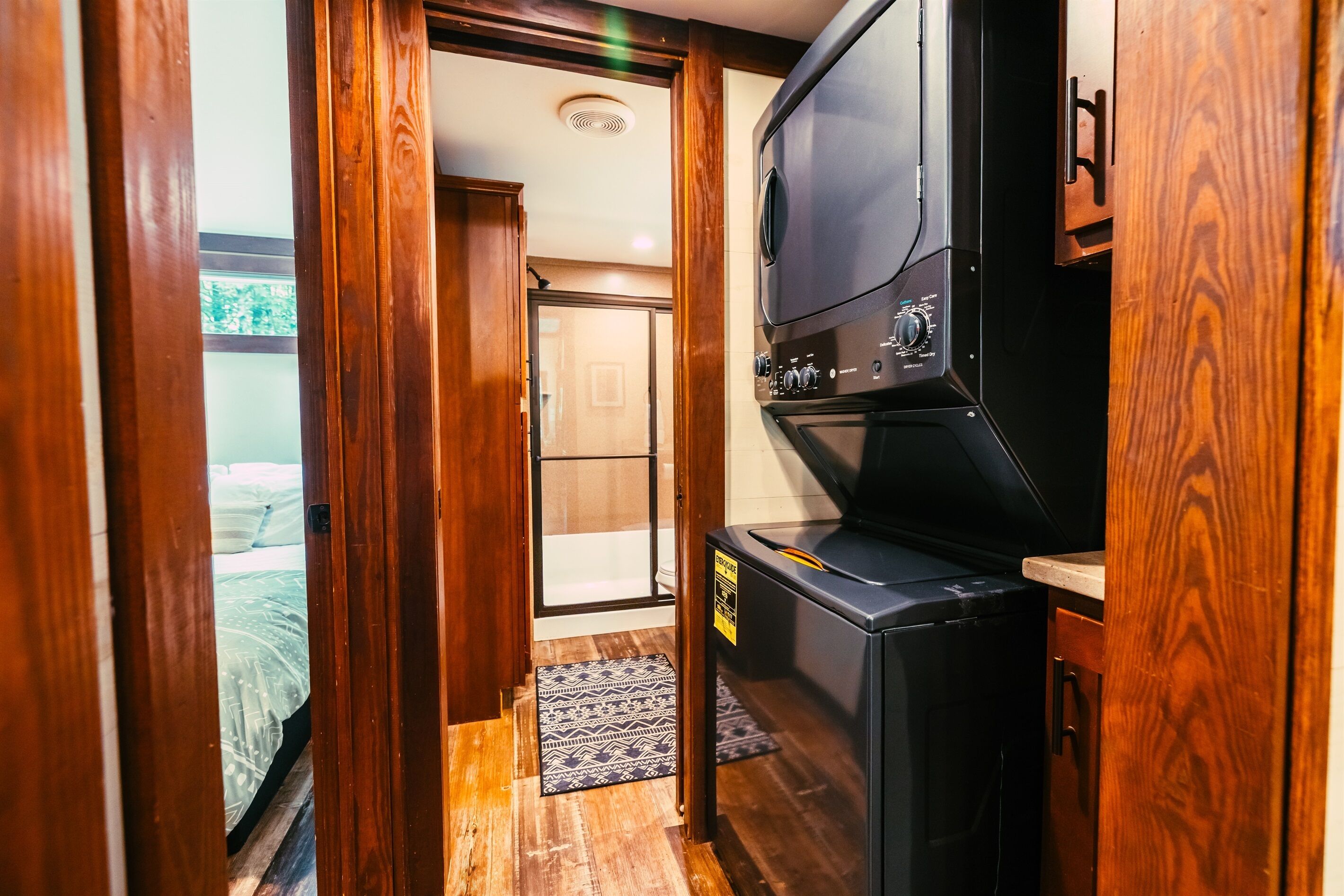 A compact room with a kitchenette, a bed, and a door leading to a bathroom.