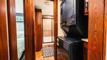 A compact room with a kitchenette, a bed, and a door leading to a bathroom.