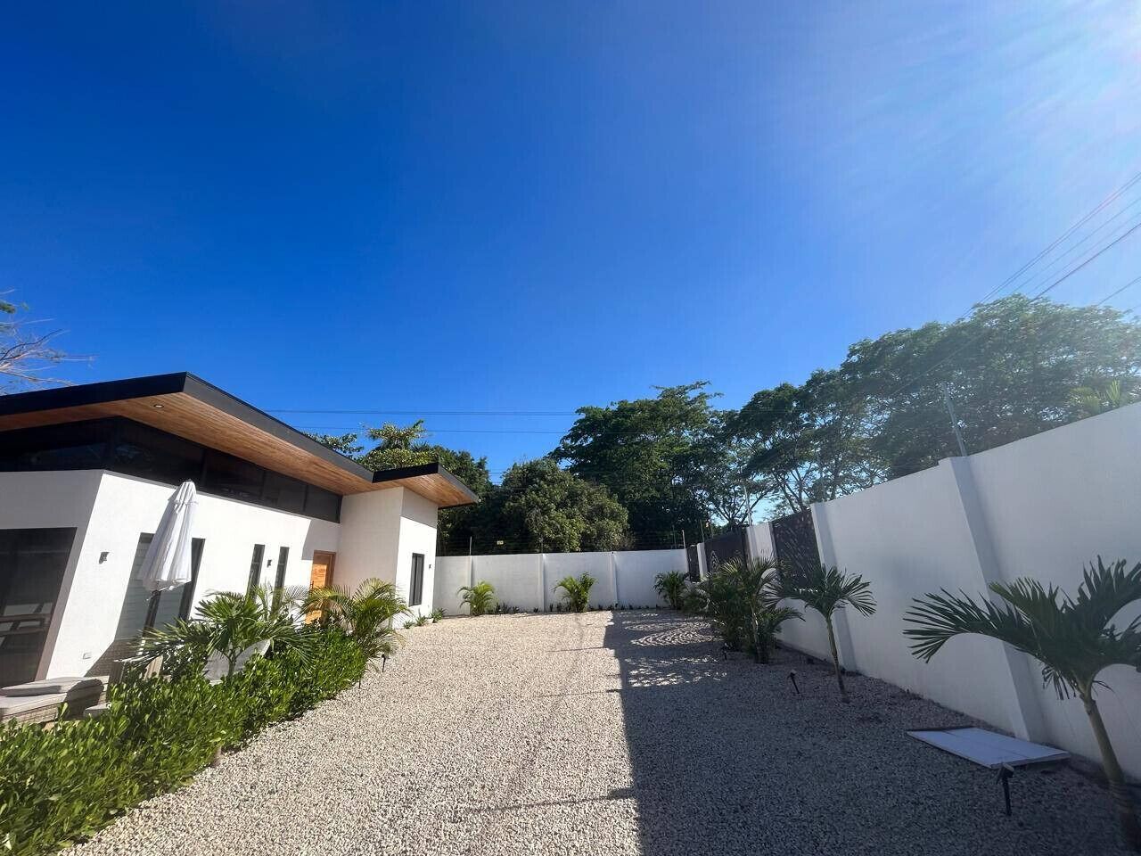 Una casa moderna amb façana blanca, carril de grava i una petita zona de pati amb taula i cadires.