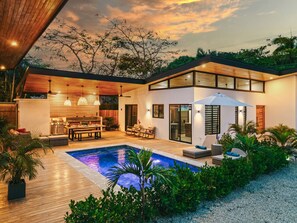 A modern house with a swimming pool, outdoor seating, and a kitchen area. - Modern Pool Villa Walk to Beach (Santa Cruz)