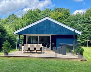 Ein modernes Haus mit überdachter Terrasse, Sitzgelegenheiten im Freien und Grillplatz.