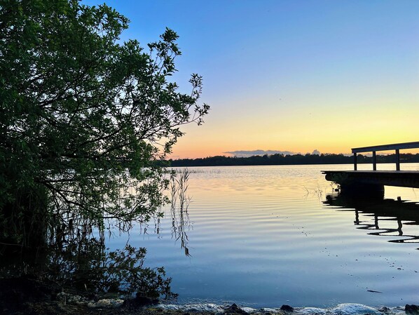 A calm lake with a wooden dock extending into the water, surrounded by dense foliage. - Renovated holiday home by Kvie Lake (Ansager)