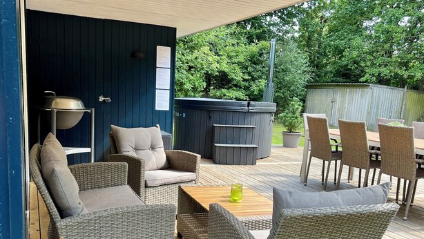 Un patio al aire libre con mobiliario de mimbre, un jacuzzi y una terraza de madera.