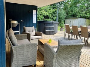 An outdoor patio with wicker furniture, a hot tub, and a wooden deck. - Renovated holiday home by Kvie Lake (Ansager)