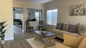 A spacious living room with a beige sofa, a coffee table, and a dining area with chairs and a plant. - 3-bedroom house with TVs, grill, private pool and WiFi in wonderful Avondale (Avondale)