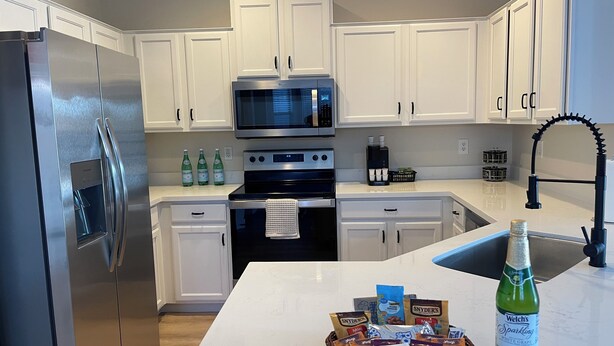 A modern kitchen with white cabinets, stainless steel appliances, a microwave, and a coffee maker. - 3-bedroom house with TVs, grill, private pool and WiFi in wonderful Avondale (Avondale)