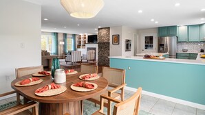 A modern kitchen with teal cabinets, a central island, and a dining area with a round table set for four.