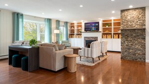 A spacious living room with a fireplace, a sofa set, a coffee table, and a television.