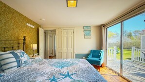 Une chambre à coucher comprenant un lit, une table de chevet, une lampe, une chaise et une vue sur l’extérieur.