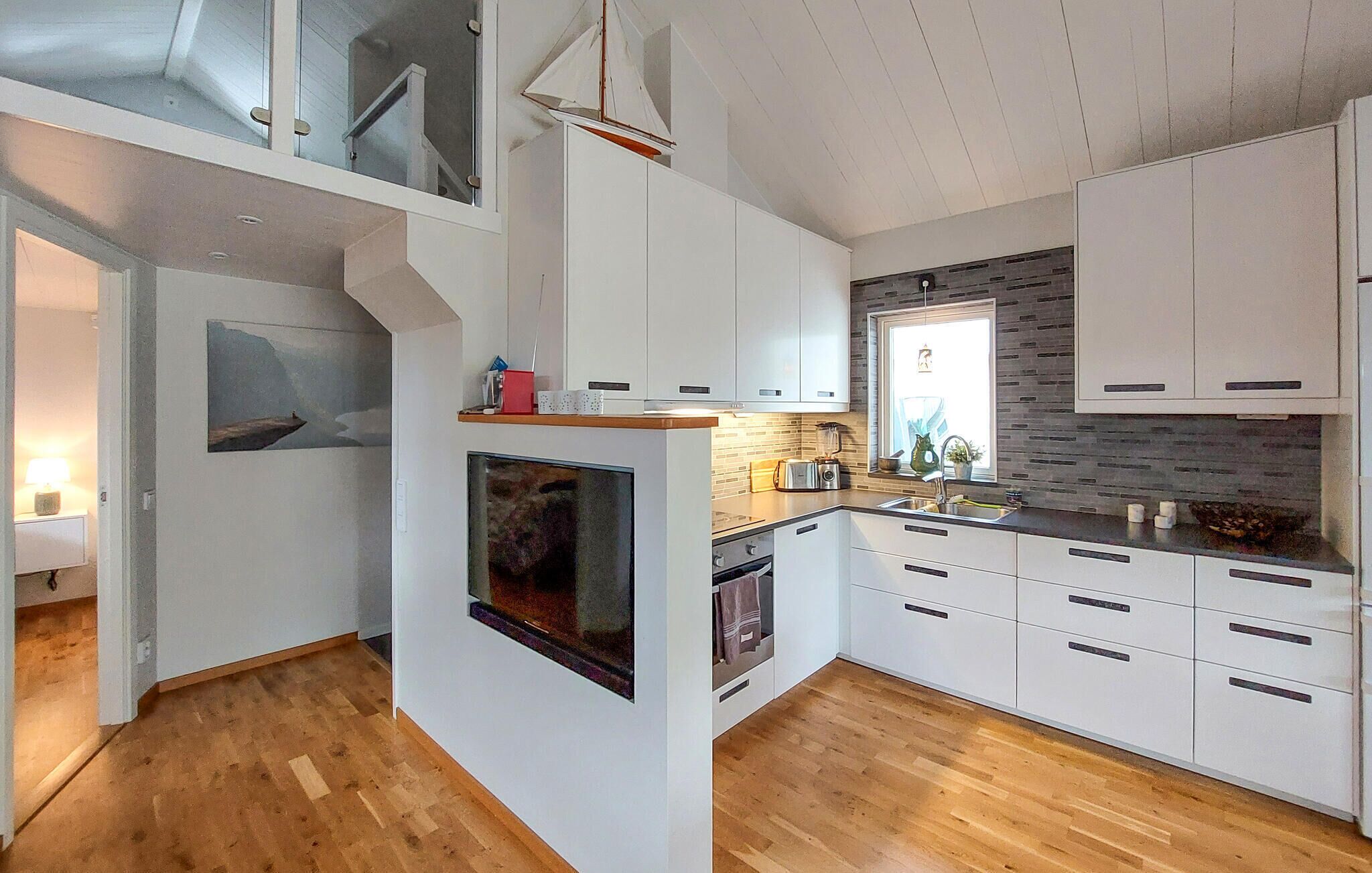 A modern kitchen with white cabinetry, a built-in oven, and a wooden floor.