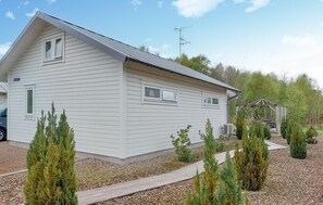 A single-story white building with a sloped roof, a small porch, and a gravel driveway.