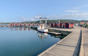 A harbor with a docked boat, red buildings, and a wooden walkway.