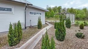 A modern house with a wooden deck, a covered outdoor seating area, and a garden with small trees. - 1 bedroom cozy home in Skummeslöv (Skummeslöv)