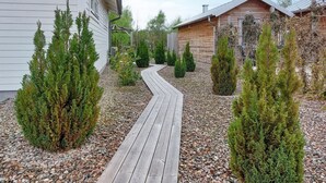 A wooden pathway leading to a cabin with a sloped roof, surrounded by evergreen shrubs and a gravel bed. - 1 bedroom cozy home in Skummeslöv (Skummeslöv)