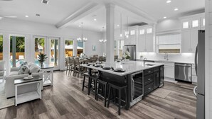 Een ruime keuken met een groot eiland, witte kasten en moderne apparatuur.