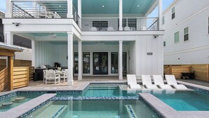 Een modern huis met twee verdiepingen, een zwembad, terras en een overdekte patio.