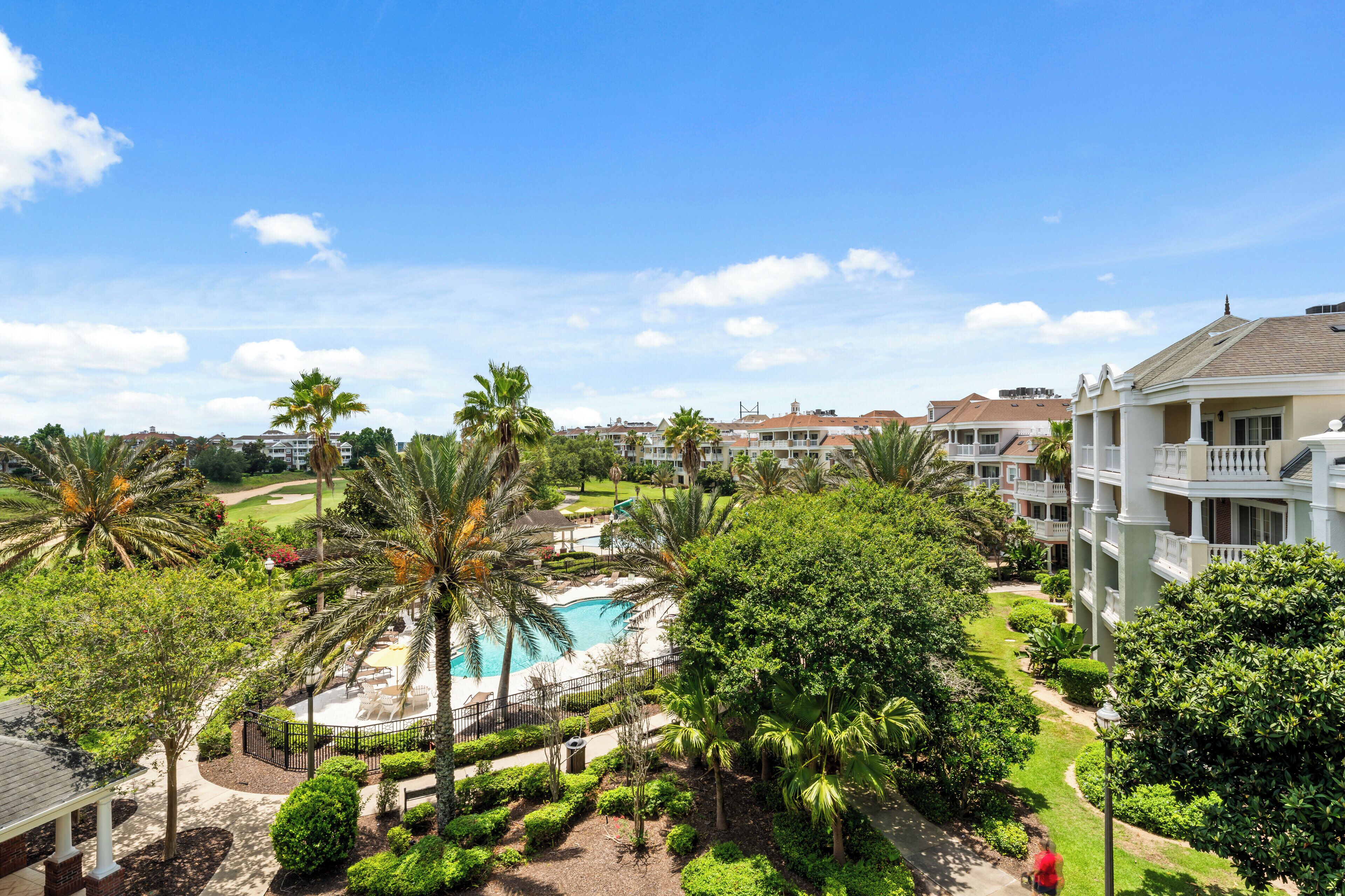 Un resort con piscina, exuberante vegetación y varios edificios con balcones.