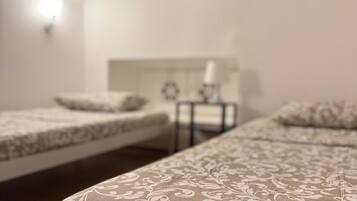 Una habitación de hotel con dos camas individuales, una mesita de noche con lámpara y una lámpara de pared.