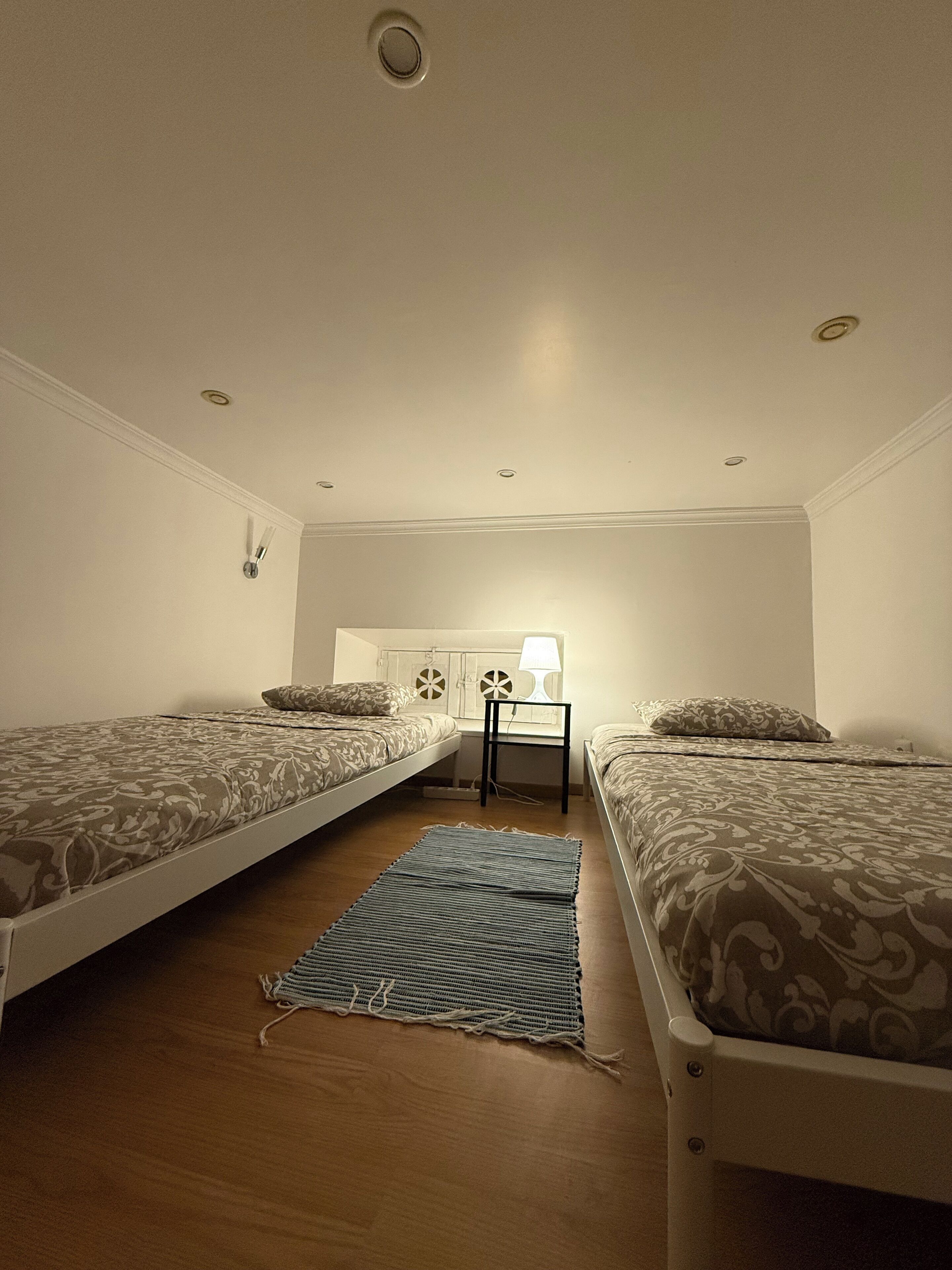 Una habitación con dos camas, un escritorio y una lámpara.