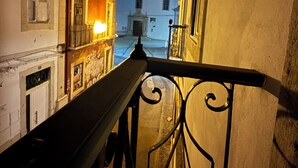 A nighttime view of a balcony with wrought iron railings overlooking a street with buildings. - Faro Coast Guest House (Faro)