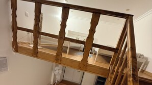 A loft bedroom with a wooden staircase, a desk, and a bed with patterned bedding. - Faro Coast Guest House (Faro)
