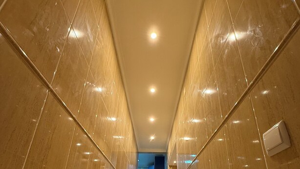A corridor with glossy tiled walls and a tiled floor, leading to a room with a blue door. - Faro Coast Guest House (Faro)
