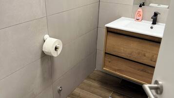 A small bathroom with a toilet, a sink, and a mirror.