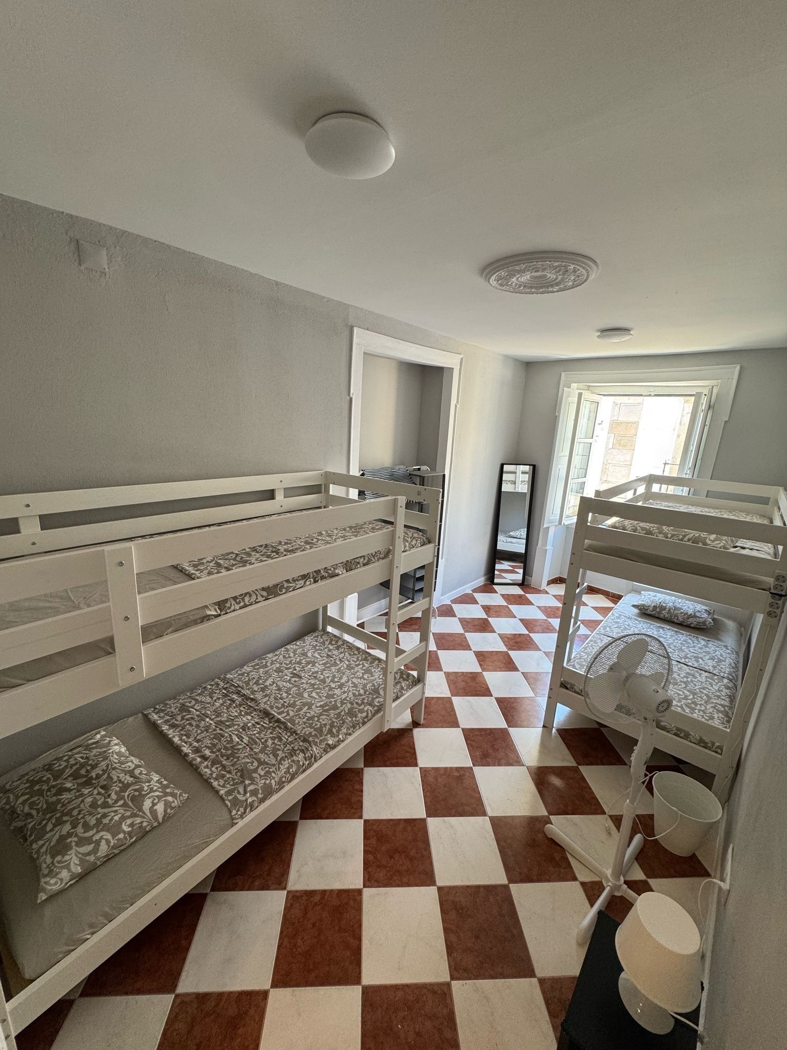 Una habitación con literas, suelo a cuadros y ventilador de techo.