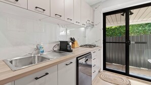 Una cocina moderna con armarios blancos, un lavamanos de acero inoxidable y un lavavajillas integrado.