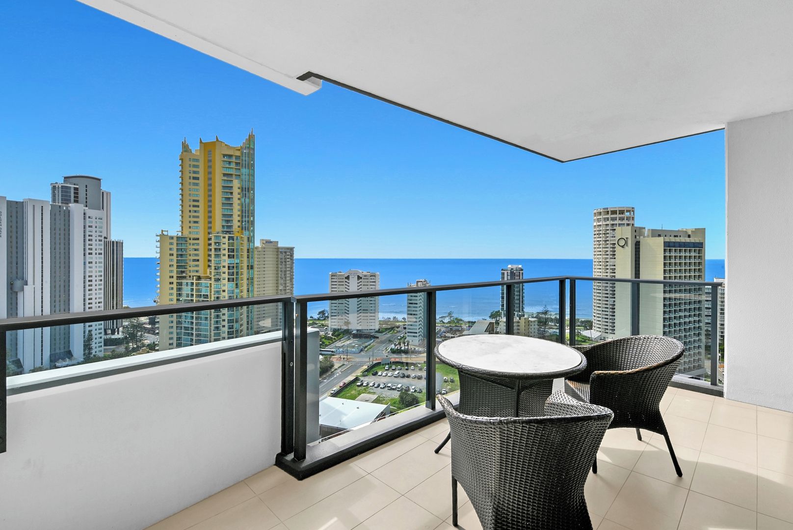A balcony with a city view, a round table, and two wicker chairs.