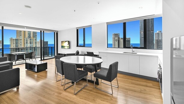 Une cuisine moderne dotée d’une grande fenêtre, un coin repas avec une table ronde et des chaises, et une vue sur le panorama urbain.